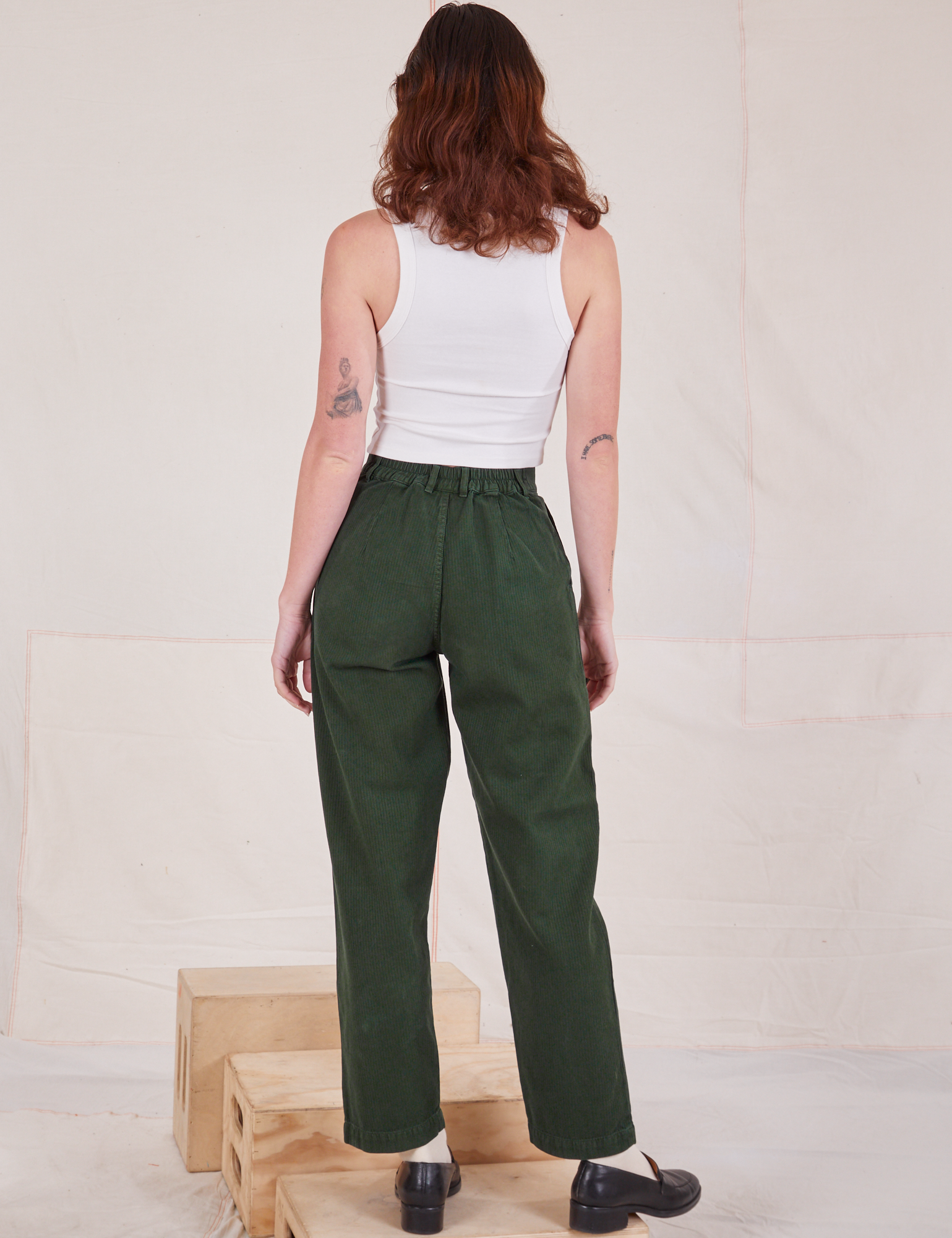 Back view of Heritage Trousers in Swamp Green and Cropped Tank Top in vintage tee off-white on Alex
