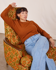 Tiara is sitting on an upholstered chair wearing Honeycomb Thermal in Burnt Terracotta