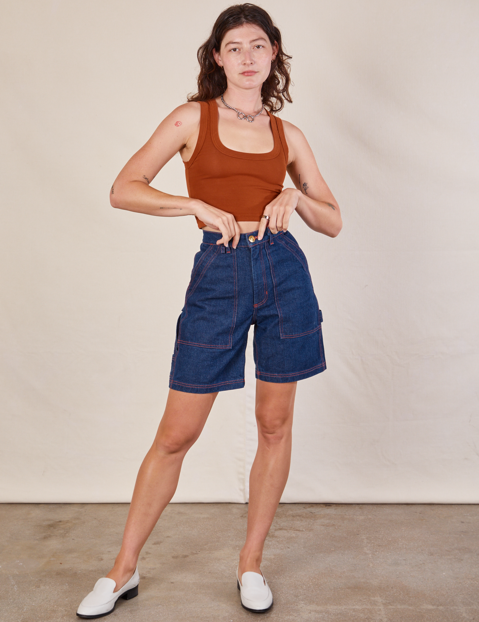 Alex is wearing Carpenter Shorts in Dark Wash and burnt terracotta Cropped Tank