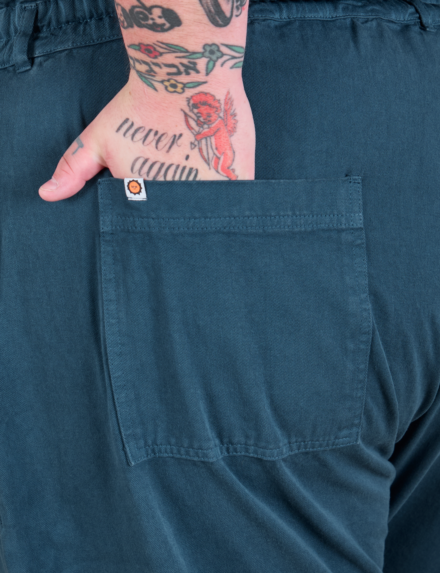 Close up of Sam's hand in the back pocket of Long Jumpsuit in Lagoon