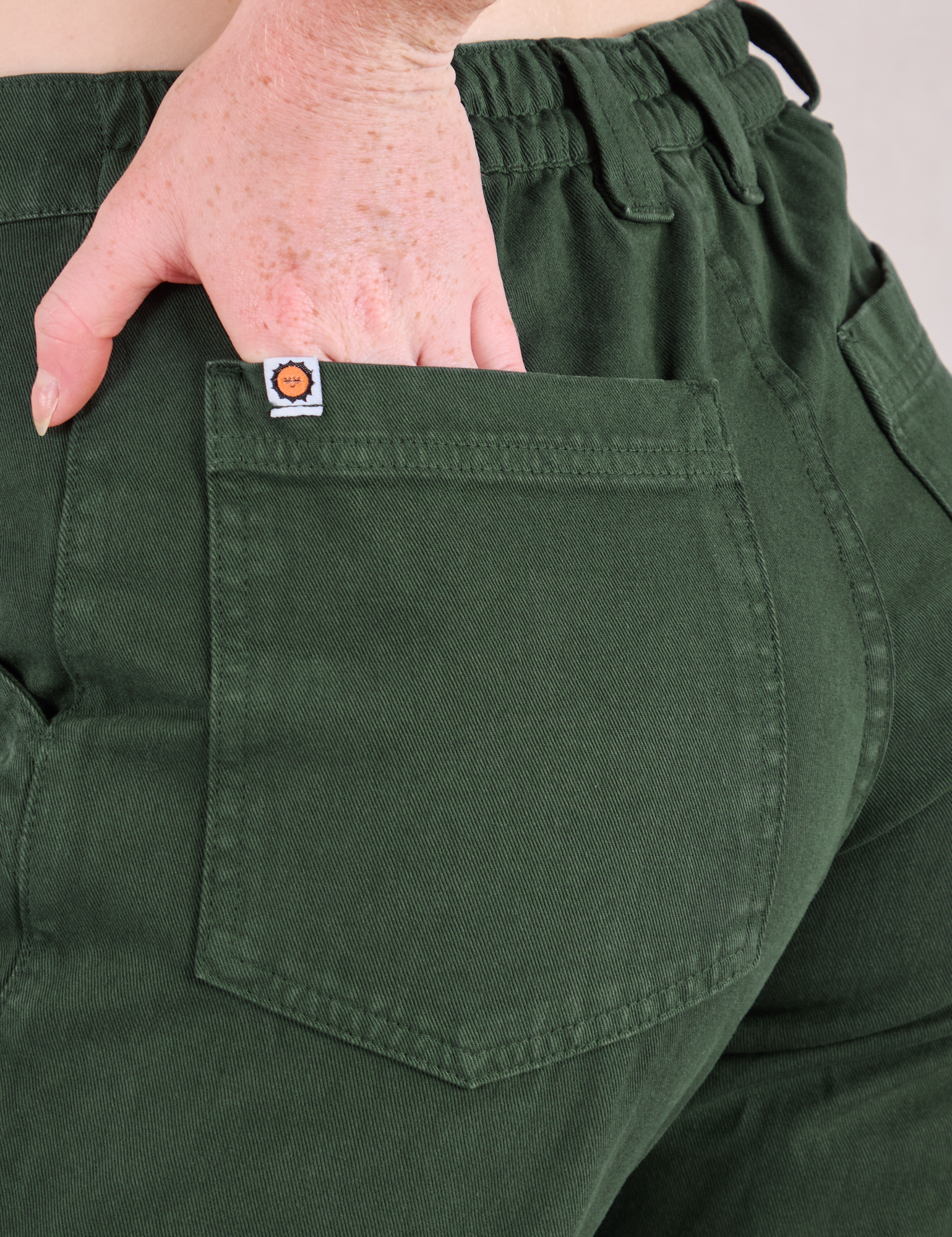 Mid-Rise Work Pants in Swamp Green close up of Margaret's hand tucked into back pocket