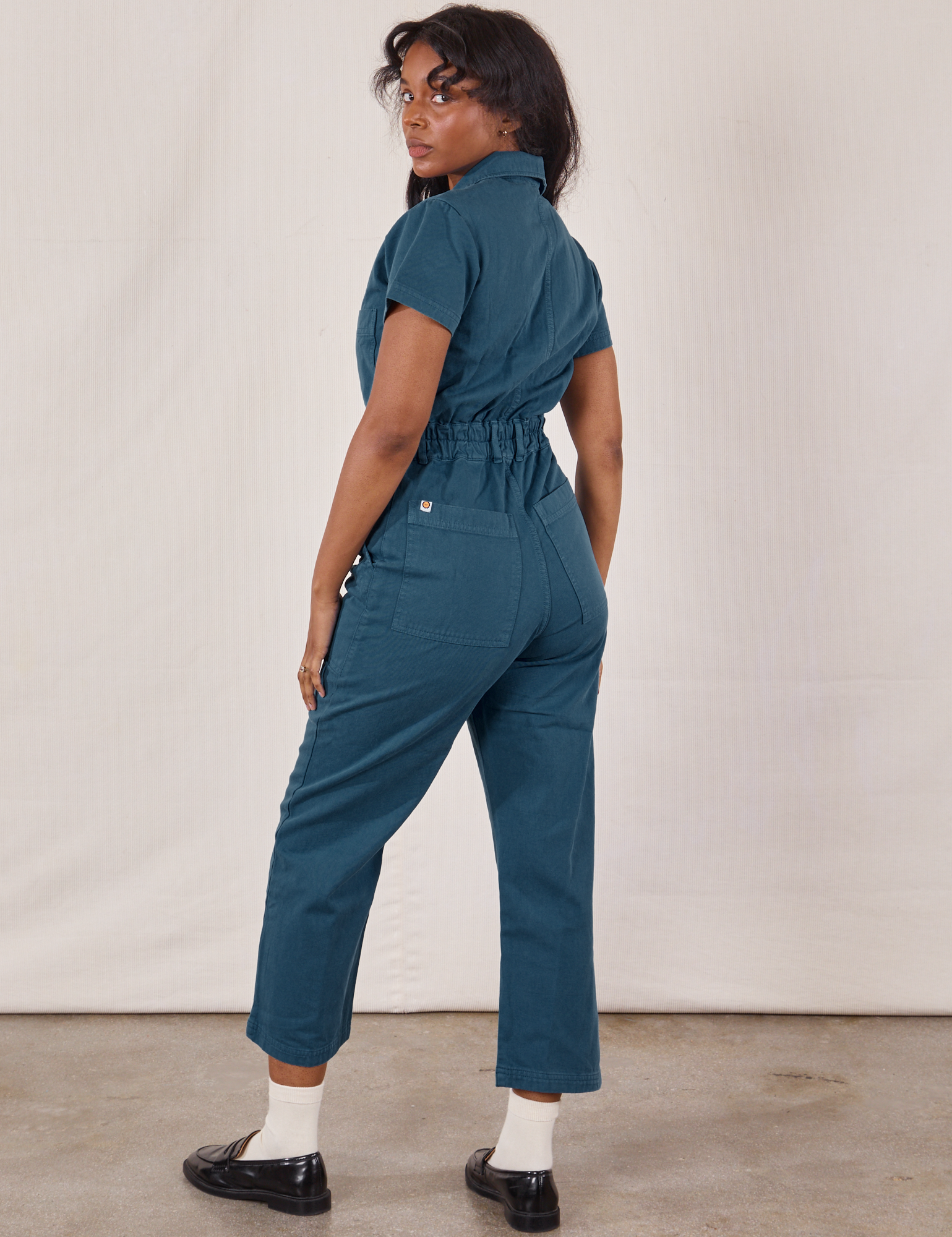 Angled back view of Petite Short Sleeve Jumpsuit in Lagoon on Kandia