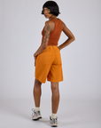 Angled back view of Longline Work Shorts in Creamsicle Orange and burnt terracotta Cropped Tank