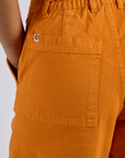 Close up of Longline Work Shorts in Creamsicle Orange back pocket on Kira