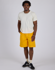 Isaac is 5’10” and wearing M Longline Work Shorts in Sunshine Yellow paired with Burly Tee in Vintage Tee White