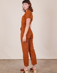 Angled back view of Short Sleeve Jumpsuit in Burnt Terracotta worn by Alex