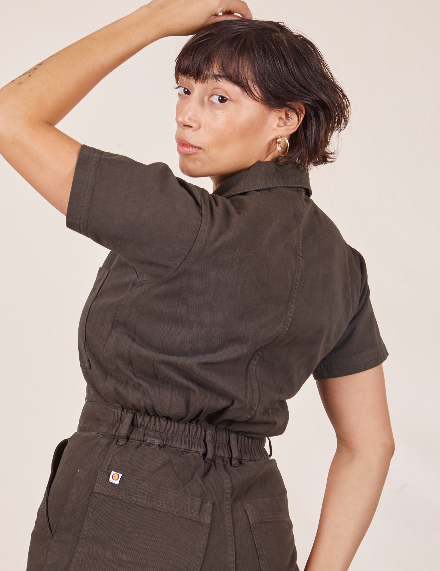 Angled back view close up of Short Sleeve Jumpsuit in Espresso Brown worn by Tiara