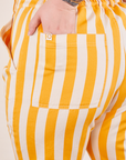 Lemon Stripe Jumpsuit back pocket close up. Sam has their hand in the pocket.