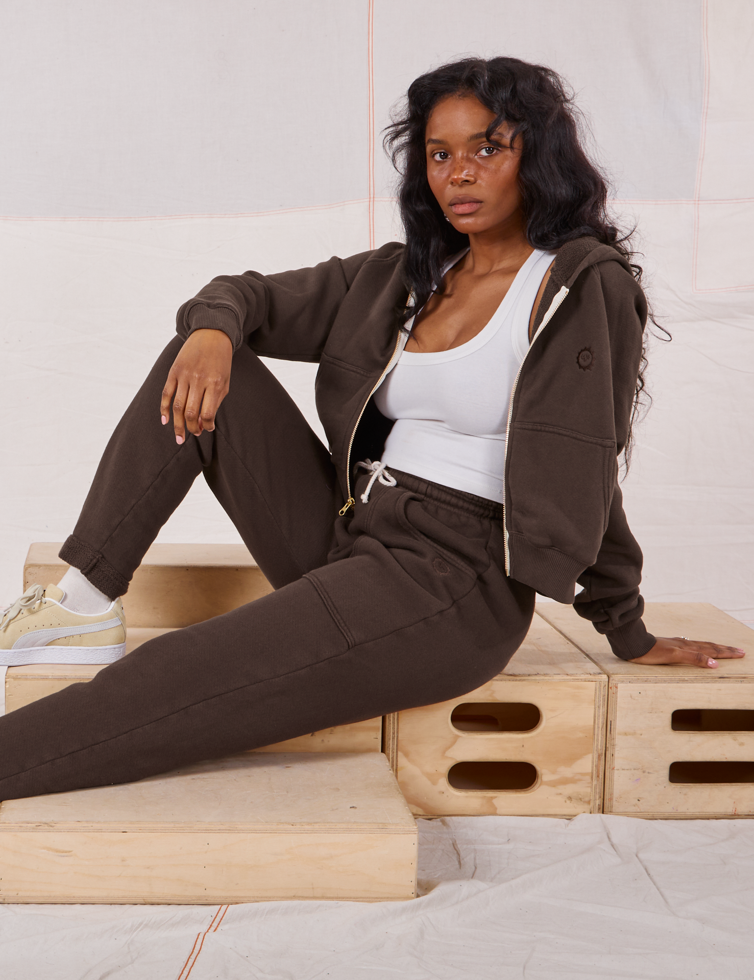 Kandia is wearing Rolled Cuff Sweat Pants in Espresso Brown and matching Cropped Zip Hoodie with a Cropped Tank in vintage tee off-white underneath