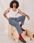 Jesse is sitting on a wooden crate wearing Denim Trouser Jeans in Railroad Stripe and Tank Top in vintage tee off-white