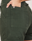 Classic Work Shorts in Swamp Green back pocket close up. Tiara has her hand in the pocket.