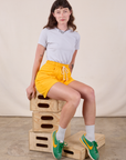 Alex is wearing Sweat Shorts in Sunshine Yellow and stone white Jr. Varsity Tee