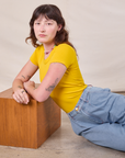 Alex is wearing Baby Tee in Golden Yellow with light wash denim Trousers