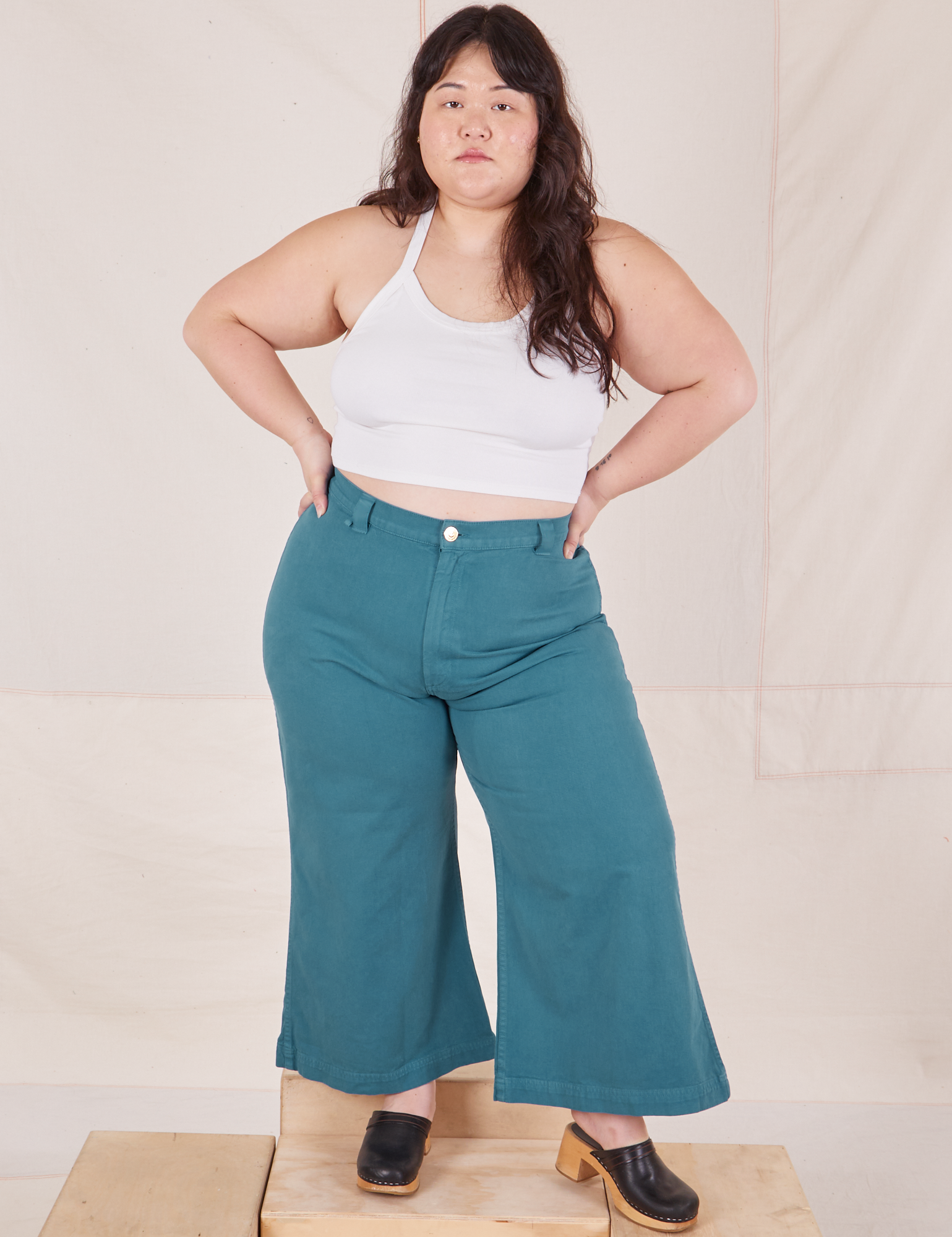 Ashley is 5&#39;7&quot; and wearing 1XL Petite Bell Bottoms in Marine Blue paired with Halter Top in vintage tee off-white