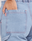 Back pocket close up of Carpenter Jeans in Light Wash. Tiara has her hand tucked into the pocket.
