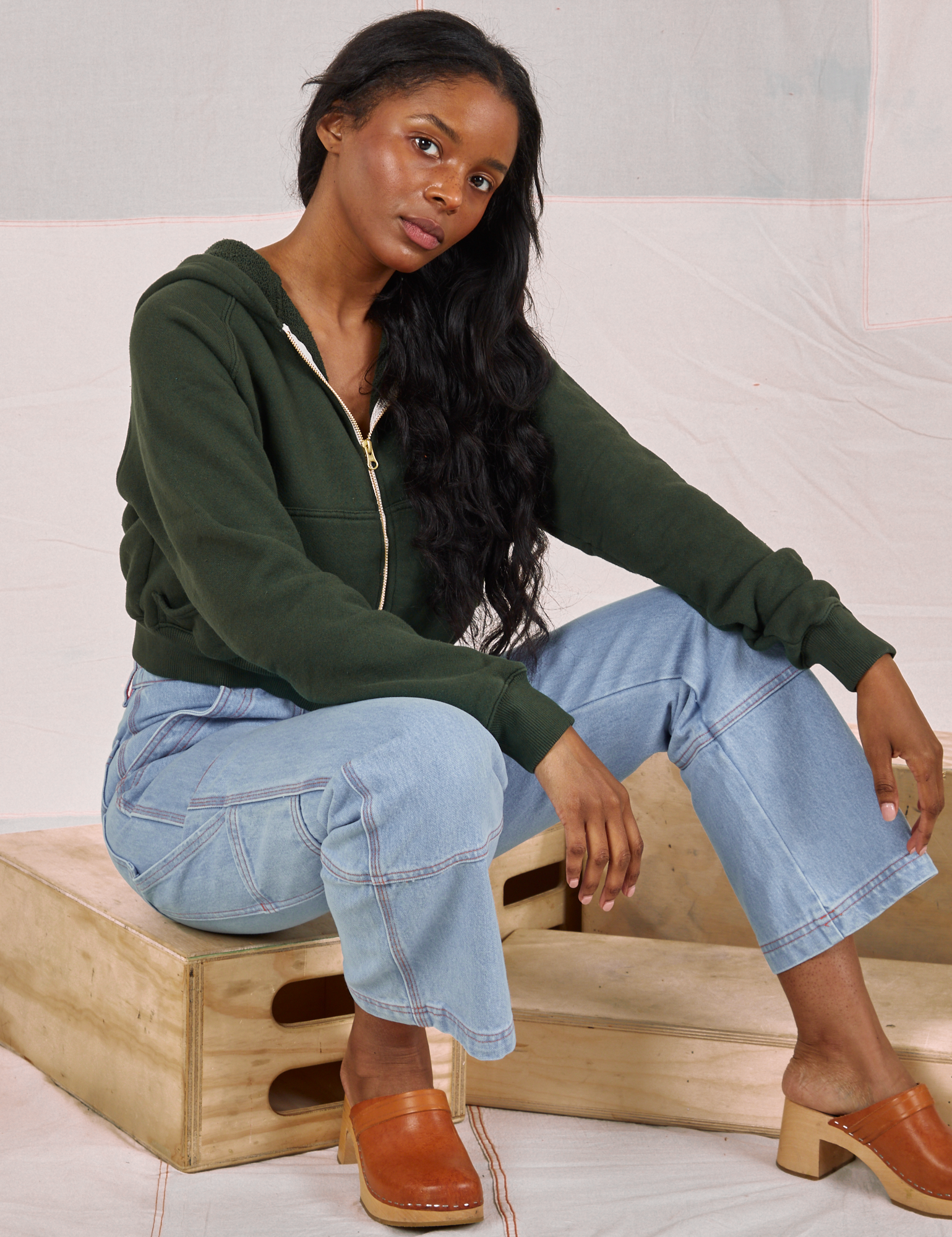 Kandia is wearing Cropped Zip Hoodie in Swamp Green and light wash Carpenter Jeans