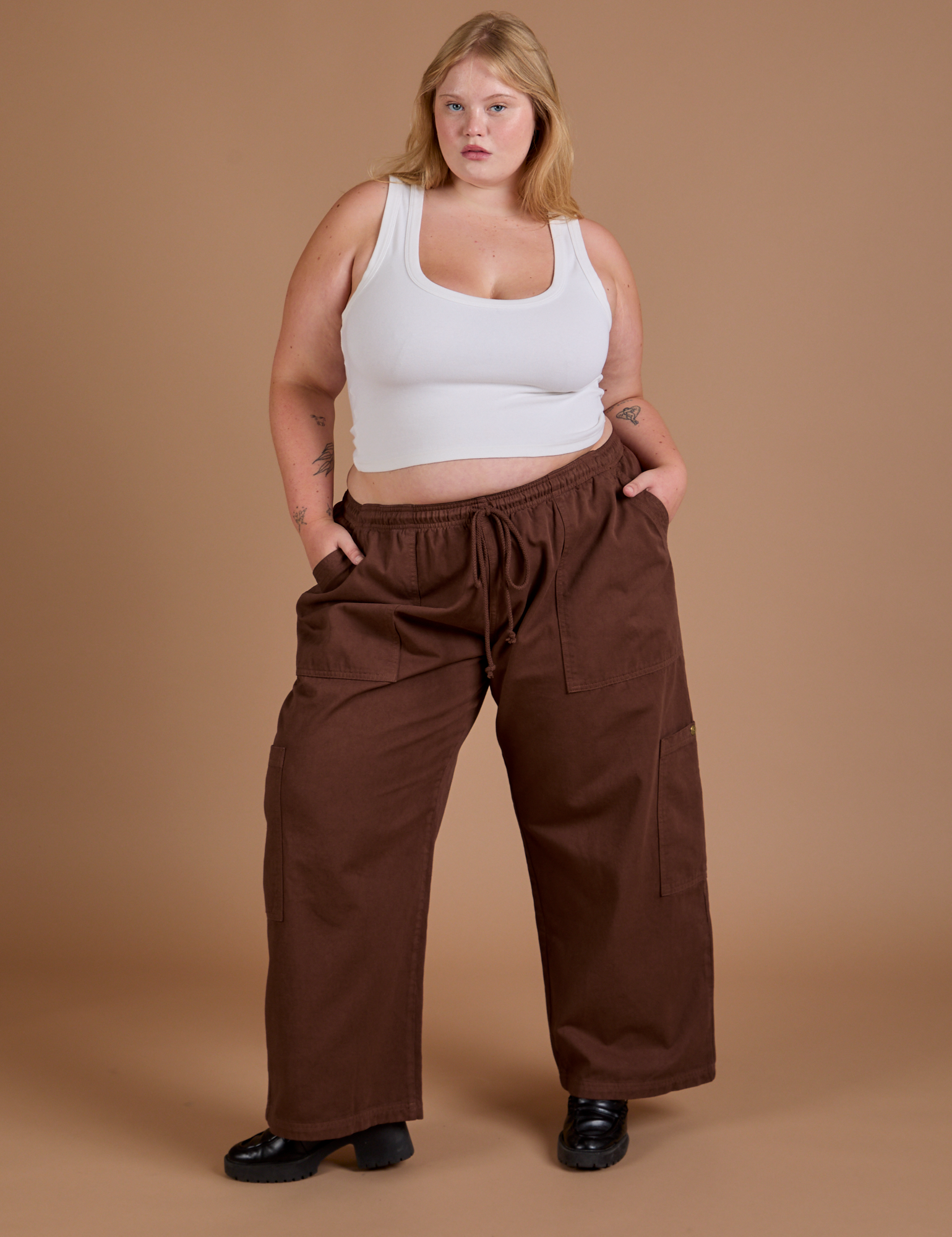 Juliet is 5’7” and wearing 1XL Drop Pocket Cargo Pants in Fudgesicle Brown paired with a Cropped Tank in vintage tee white