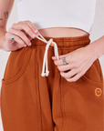 Rolled Cuff Sweat Pants in Burnt Terracotta front close up. Alex is holding the drawstring in her hands.