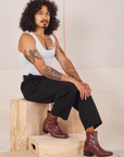 Jesse is sitting on a wooden crate wearing Heavyweight Trousers in Basic Black and Cropped Tank Top in vintage tee off-white