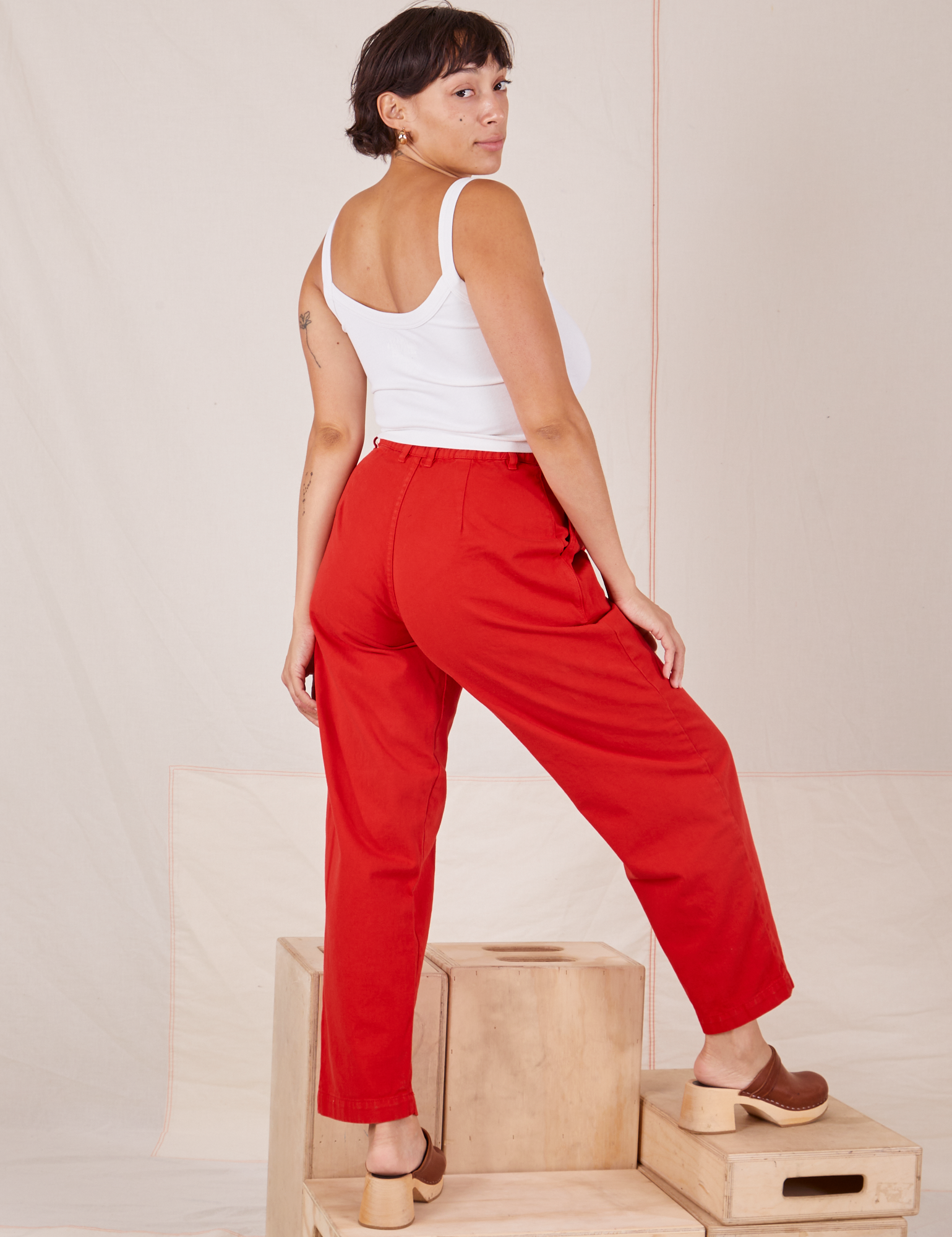 Angled back view of Heavyweight Trousers in Mustang Red and Cropped Cami in vintage tee off-white worn by Tiara