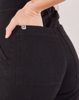Heritage Short Sleeve Jumpsuit in Basic Black back pocket close up. Alex has her hand in the pocket.