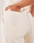 Heritage Short Sleeve Jumpsuit in Natural back pocket close up. Mika's hand is in the pocket.