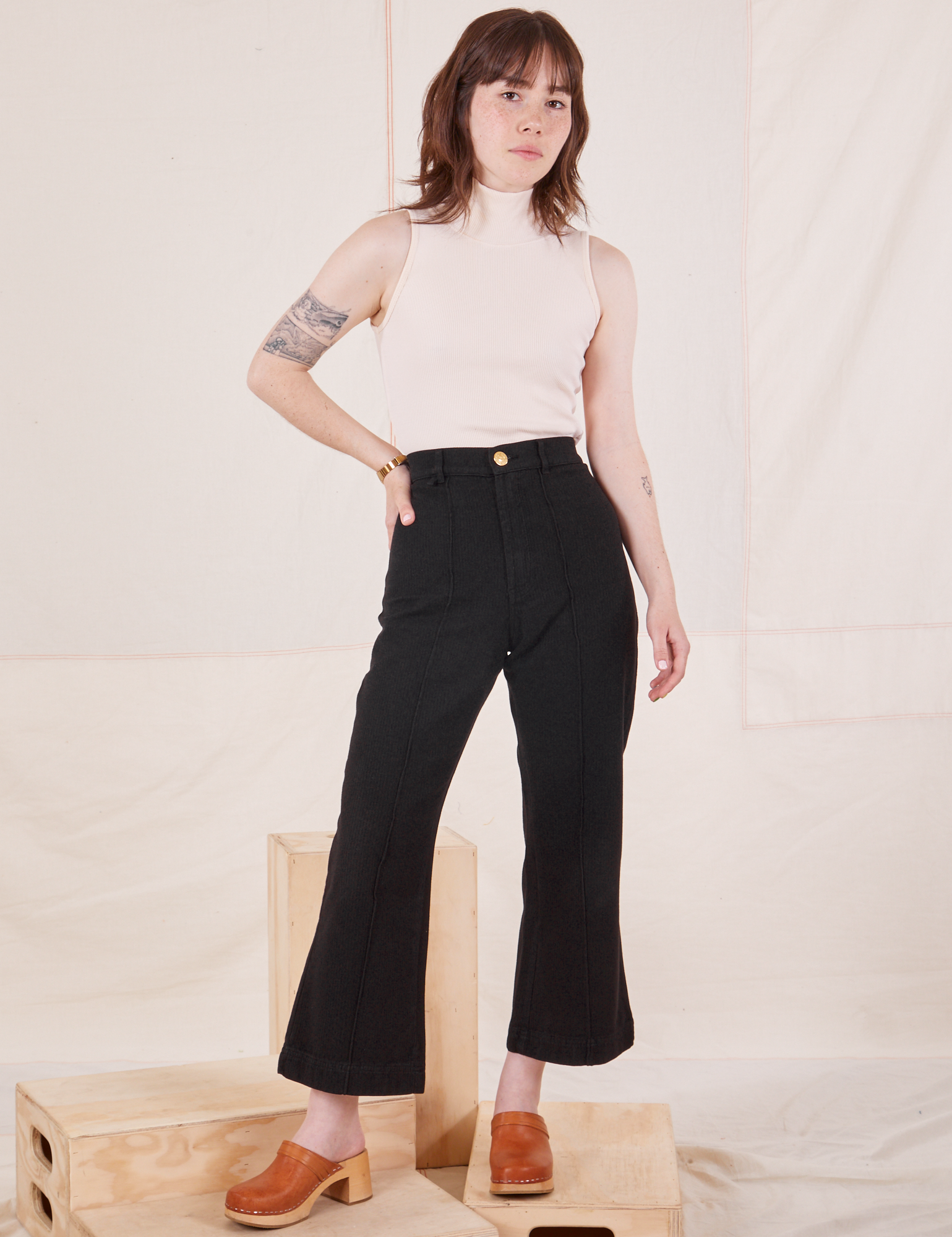 Hana is 5&#39;3&quot; and wearing XXS Petite Heritage Westerns in Basic Black paired with Sleeveless Turtleneck in vintage tee off-white