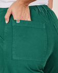 Back pocket close up of Work Pants in Hunter Green. Tiara has her hand in the pocket.