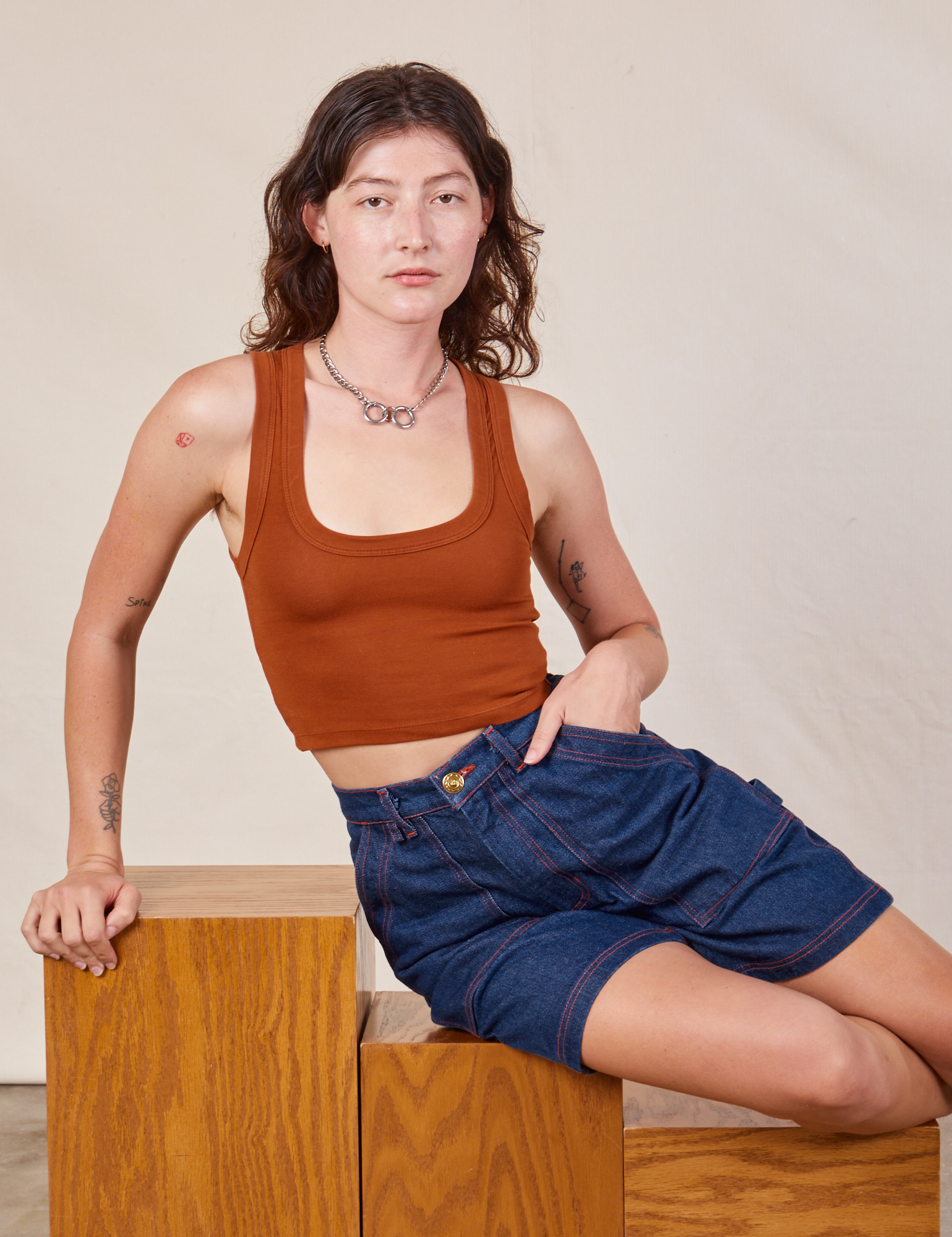 Alex is wearing Carpenter Shorts in Dark Wash and burnt terracotta Cropped Tank