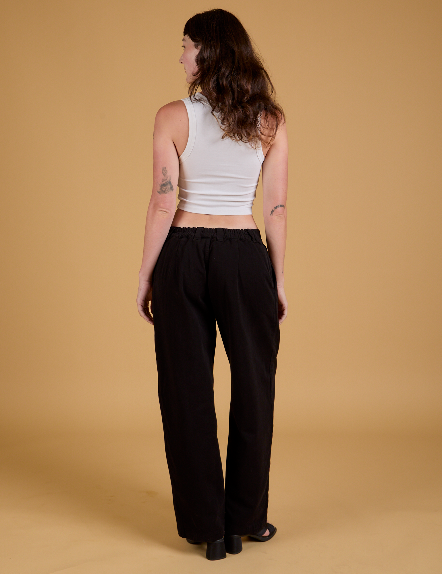 Back view of Baggy Mid-Rise Trousers in Basic Black and vintage tee white Cropped Tank on Alex