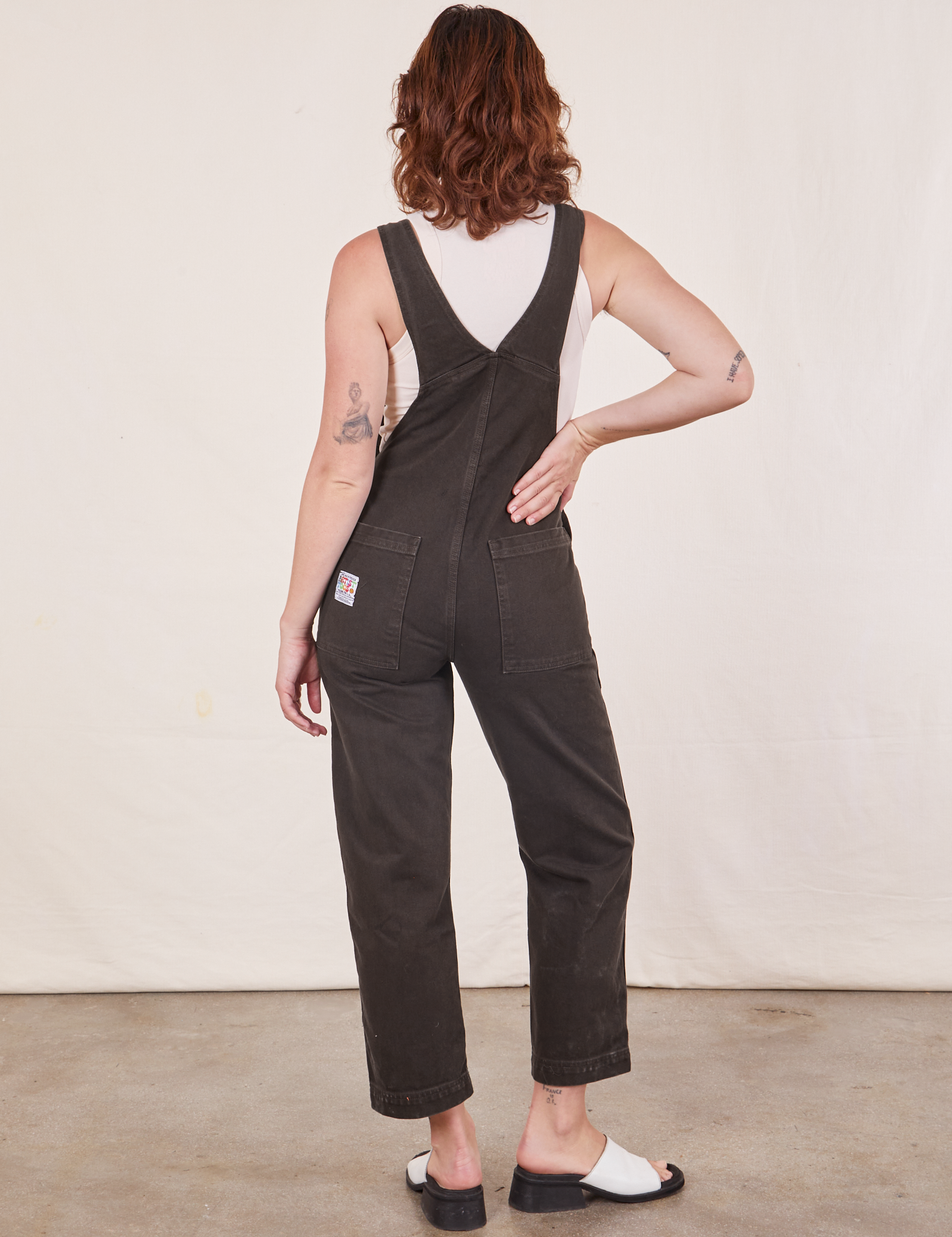 Back view of Original Overalls in Mono Espresso and Cropped Tank Top in vintage tee off-white worn by Alex.