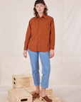 Alex is wearing a buttoned up Oversize Overshirt in Burnt Terracotta paired with light wash Frontier Jeans