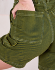 Close up of Alex's hand in the back pocket of Railroad Carpenter Shorts in Summer Olive