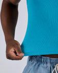 Close up of Isaac tugging on the bottom hem of Cropped Tank Top in Hawaiian Blue