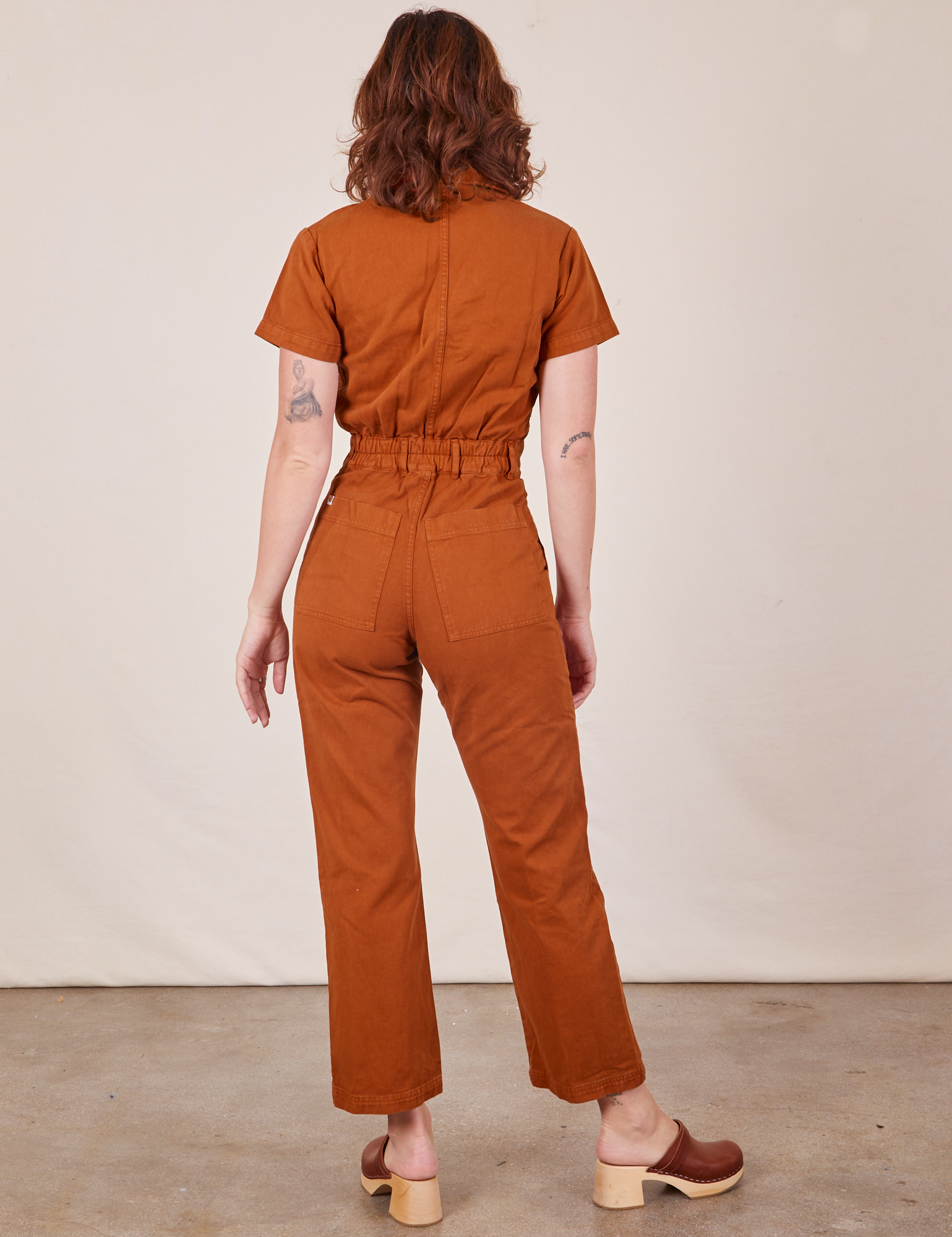 Back view of Short Sleeve Jumpsuit in Burnt Terracotta worn by Alex