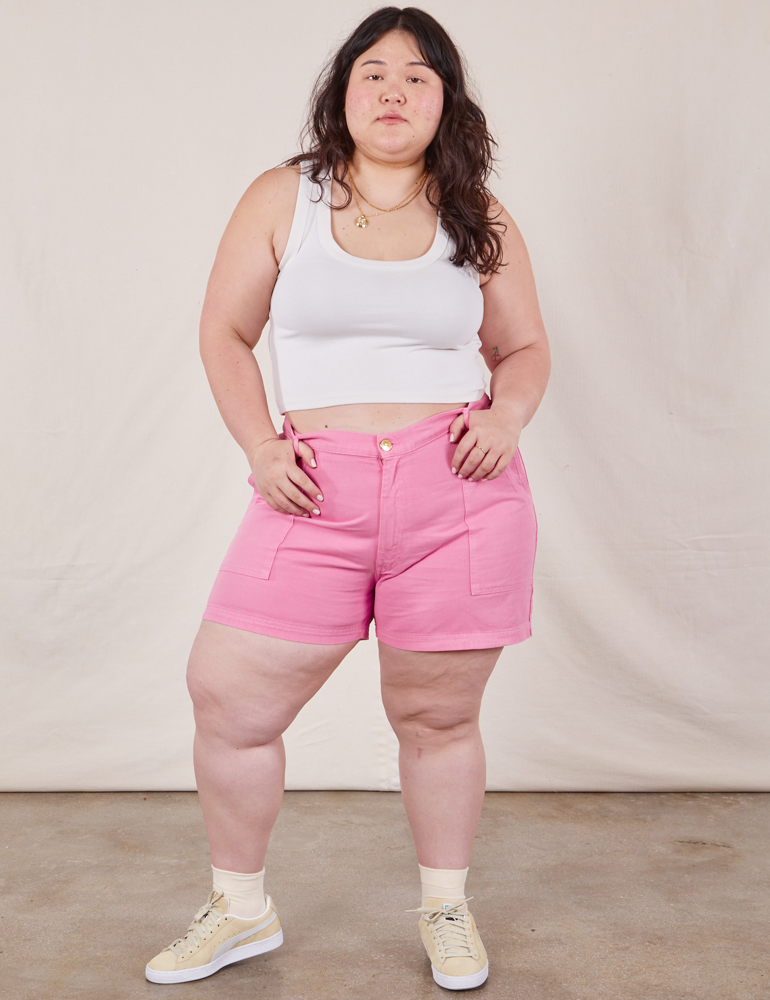 Ashley is 5’7” and wearing 1XL Classic Work Shorts in Bubblegum Pink paired with Cropped Tank Top in vintage tee off-white