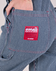 Close up of Alex's hand in the back pocket of Carpenter Overalls in Railroad