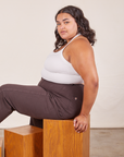 Alicia is sitting on a wooden box facing the left. She is wearing Halter Top in Vintage Off-White and espresso brown Western Pants