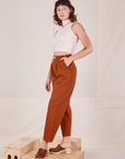 Angled view of Heavyweight Trousers in Burnt Terracotta and vintage off-white Sleeveless Turtleneck worn by Alex