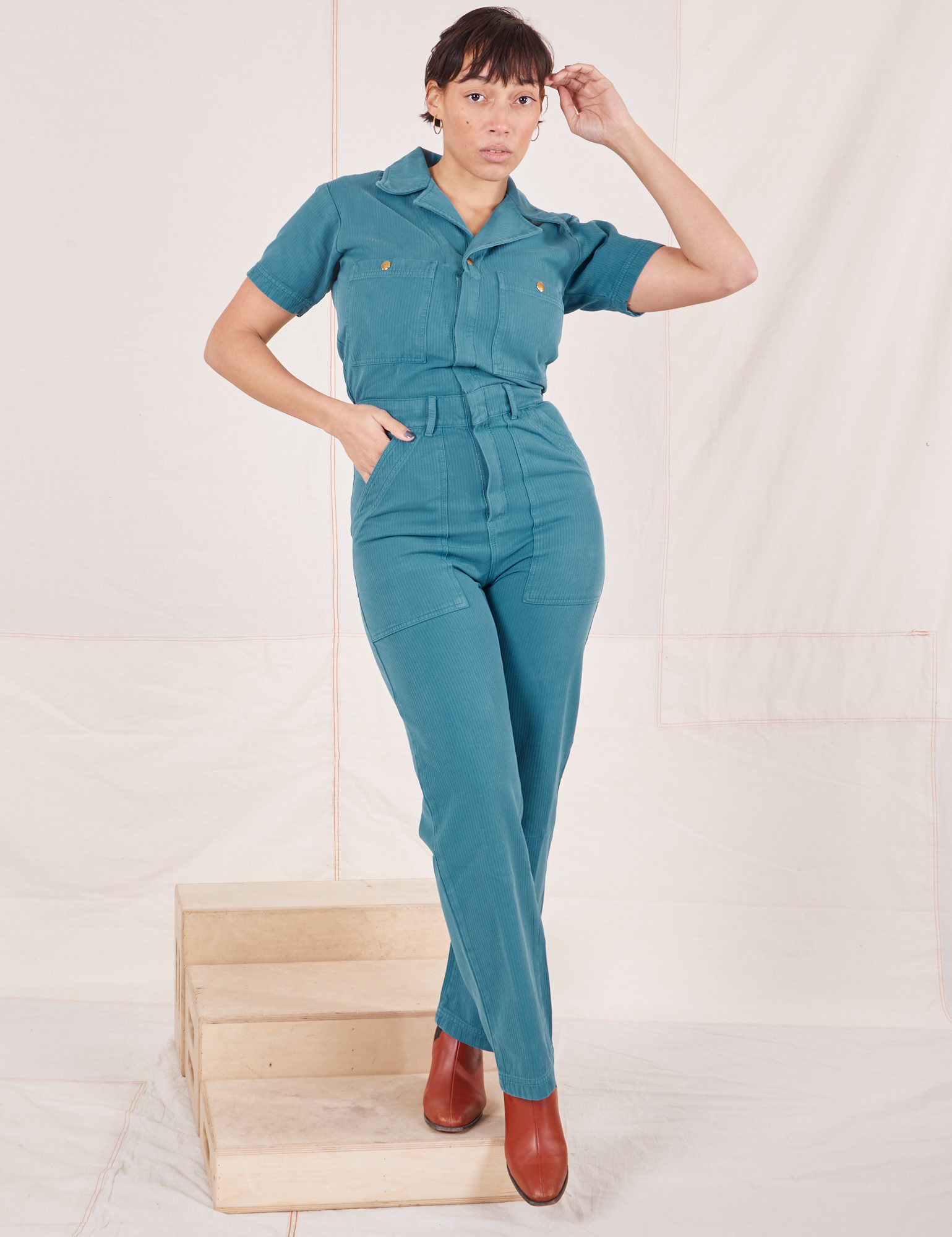 Tiara is 5&#39;4&quot; and wearing size S Heritage Short Sleeve Jumpsuit in Marine Blue
