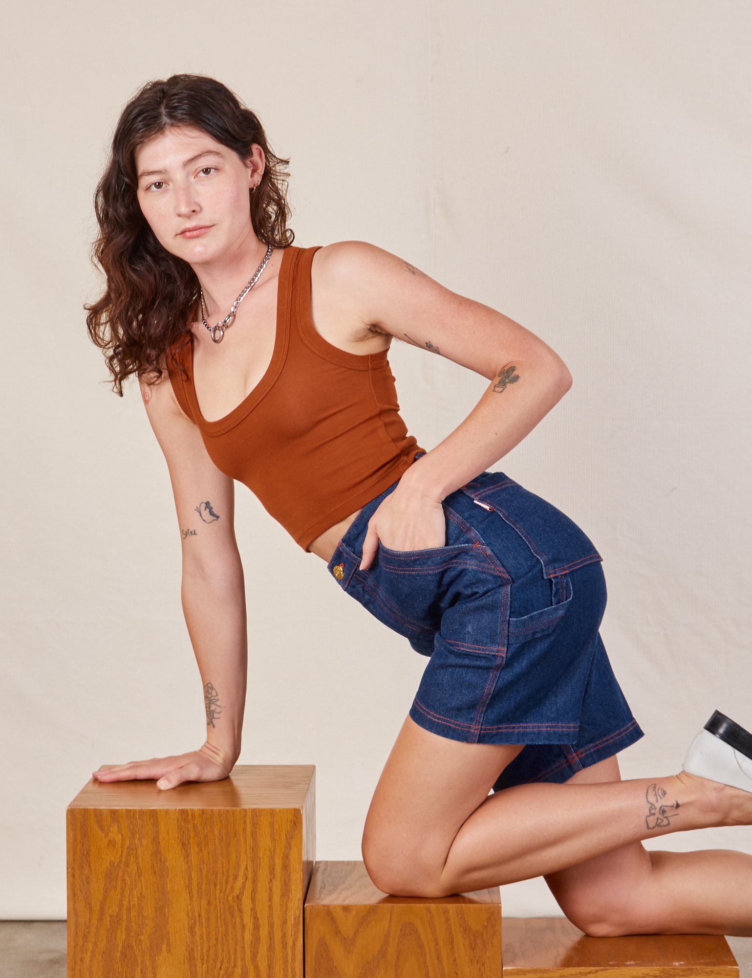 Alex is wearing Carpenter Shorts in Dark Wash and burnt terracotta Cropped Tank