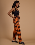 Side view of Black Stripe Work Pants in Construction Orange on Kandia and black cropped tank