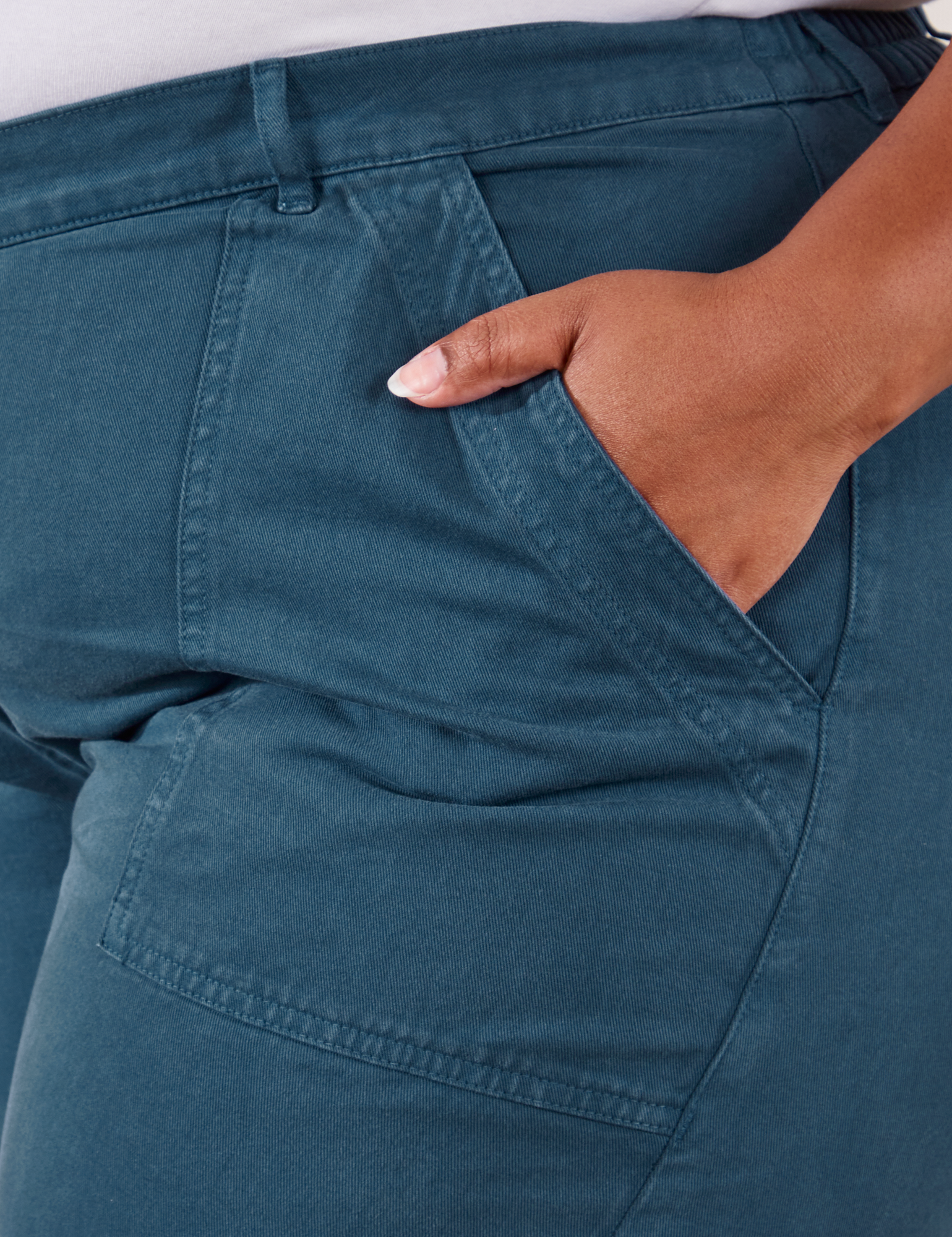 Work Pants in Lagoon front pocket close up. Morgan has their hand in the pocket.