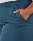 Work Pants in Lagoon front pocket close up. Morgan has their hand in the pocket.
