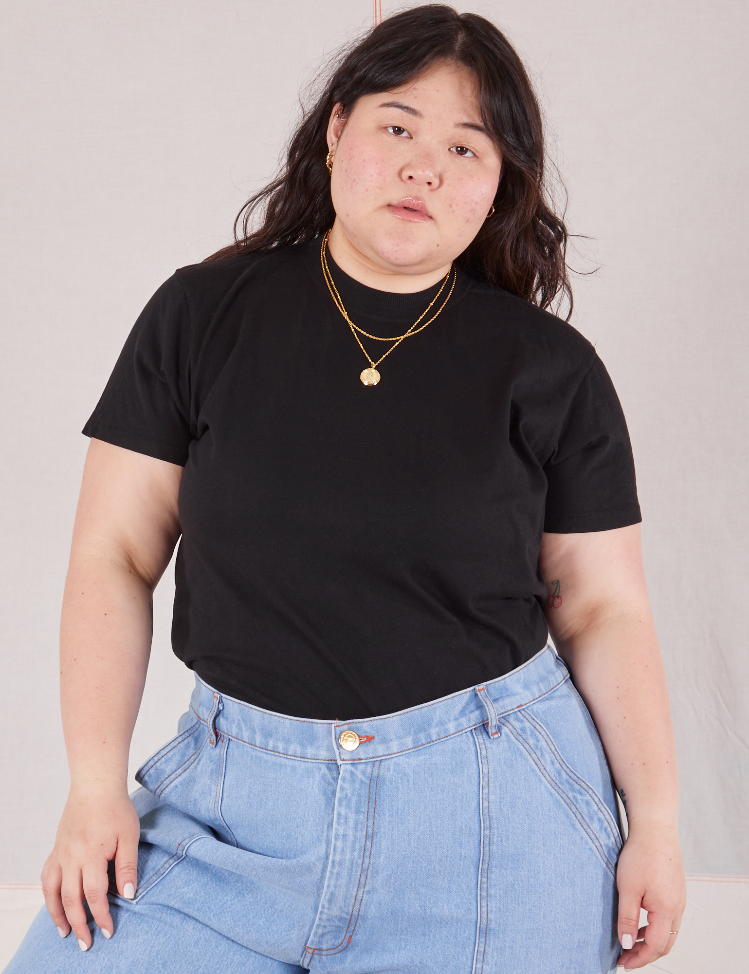 Ashley is 5'7" and wearing L Organic Vintage Tee in Basic Black tucked into light wash Carpenter Jeans