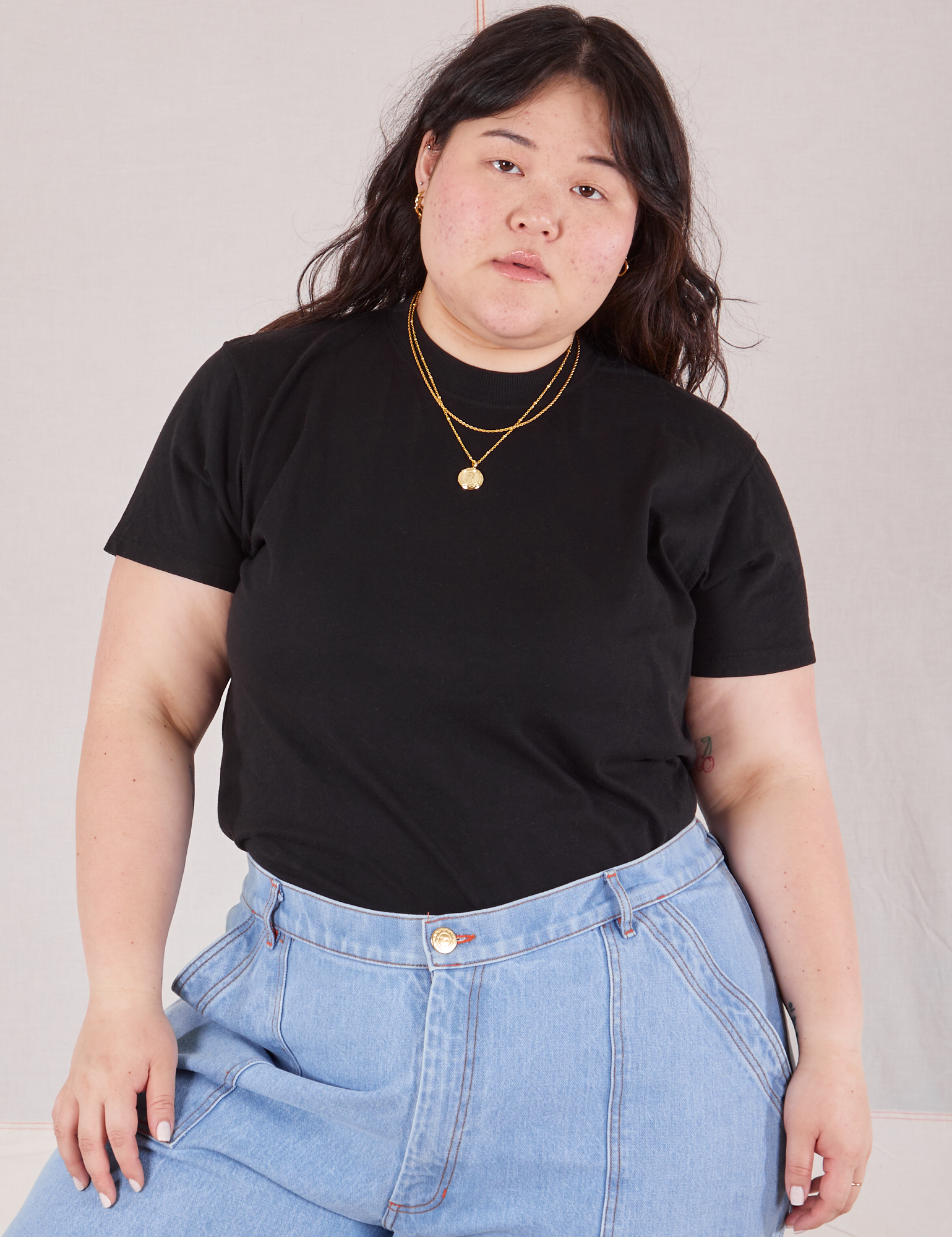 Ashley is 5&#39;7&quot; and wearing L Organic Vintage Tee in Basic Black tucked into light wash Carpenter Jeans