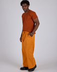 Side view of Drop Pocket Cargo Pants in Creamsicle Orange and burnt terracotta Organic Vintage Tee on Isaac