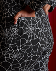 Close up of Kandia's hand in the back pocket of Everyday Jumpsuit in Spiderwebs