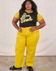 Morgan is wearing Anniversary Tee in I’m Tired tucked into golden yellow Work Pants