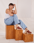 Tiara is sitting on a wooden box wearing Carpenter Jeans in Light Wash